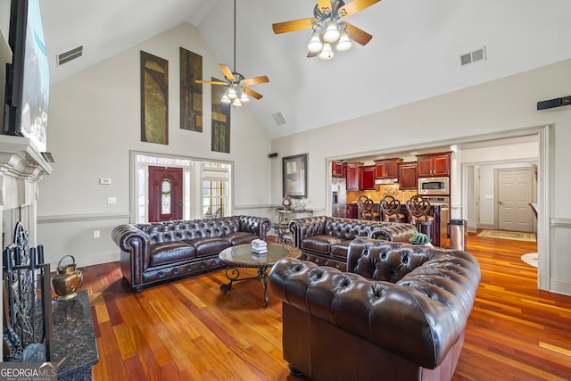 living room featuring ceiling fan, high vaulted ceiling, and light hardwood / wood-style flooring