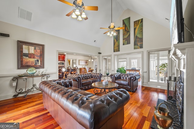 living room featuring high vaulted ceiling, ceiling fan, visible vents, and wood finished floors