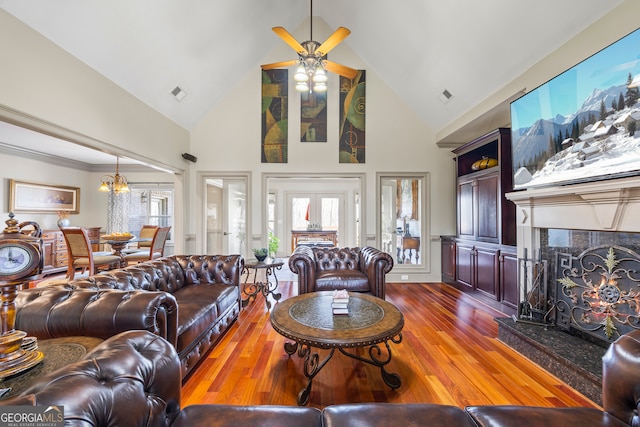 living room with a tiled fireplace, wood-type flooring, high vaulted ceiling, and ceiling fan