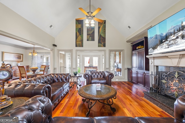 living room featuring high vaulted ceiling, a fireplace, visible vents, and wood finished floors