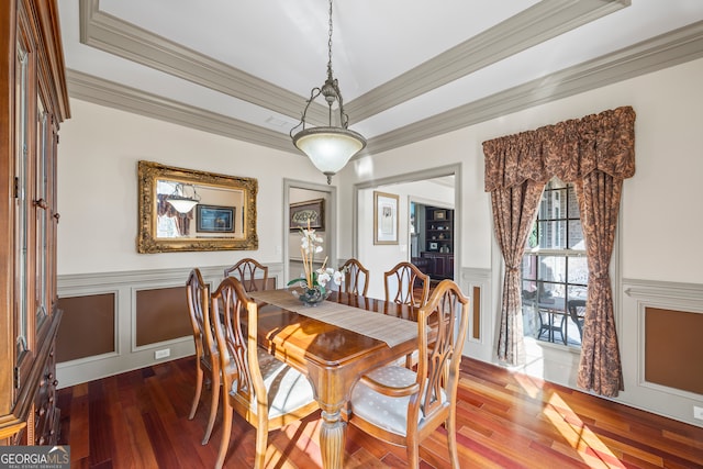 dining area featuring a wainscoted wall, ornamental molding, a decorative wall, and wood finished floors