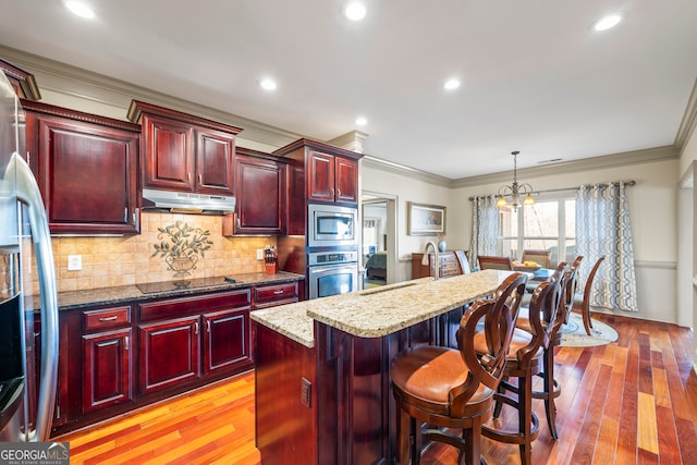 kitchen featuring a kitchen breakfast bar, stainless steel appliances, dark stone counters, and a kitchen island