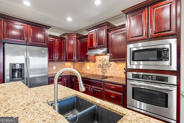 kitchen featuring light stone counters, sink, decorative backsplash, and stainless steel appliances