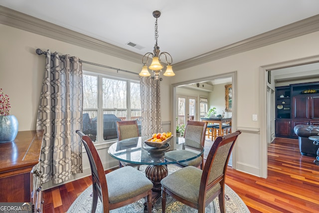 dining area featuring ornamental molding, visible vents, baseboards, and wood finished floors