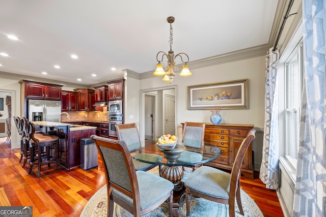 dining room with ornamental molding, dark hardwood / wood-style floors, sink, and a chandelier