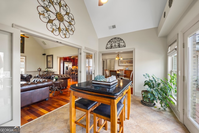 dining area featuring high vaulted ceiling and light tile patterned flooring