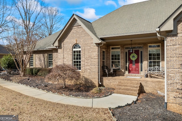 ranch-style home featuring brick siding and roof with shingles