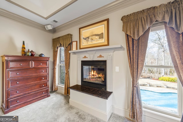 interior space featuring light carpet, visible vents, baseboards, ornamental molding, and a glass covered fireplace