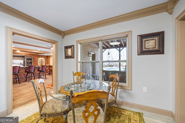dining area featuring light wood-type flooring, baseboards, and crown molding