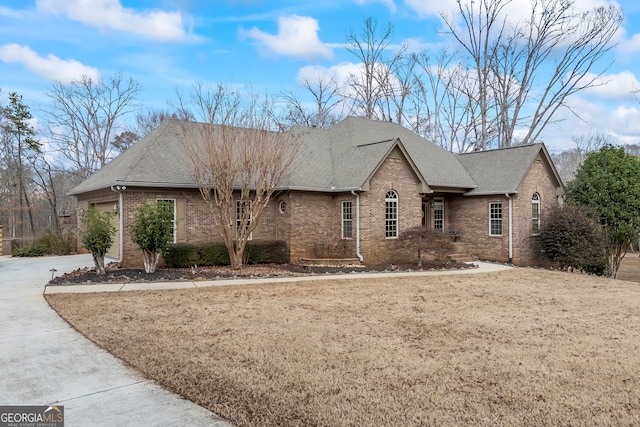 view of front of house featuring driveway, roof with shingles, a front lawn, and brick siding