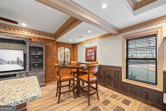 dining room featuring crown molding, brick wall, and light hardwood / wood-style floors