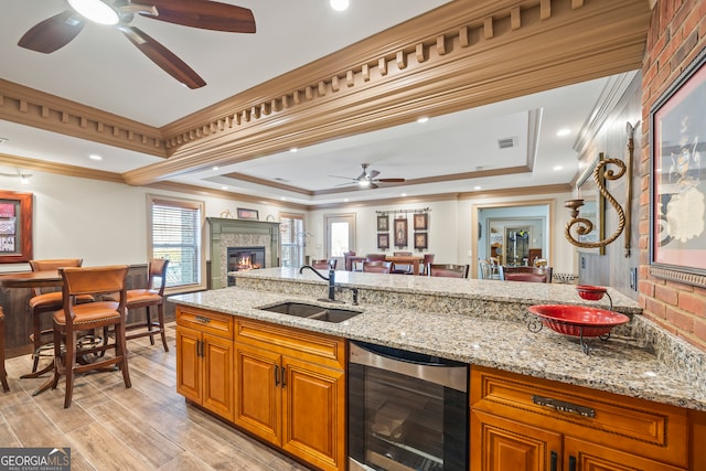 kitchen featuring wine cooler, light stone counters, a sink, visible vents, and open floor plan