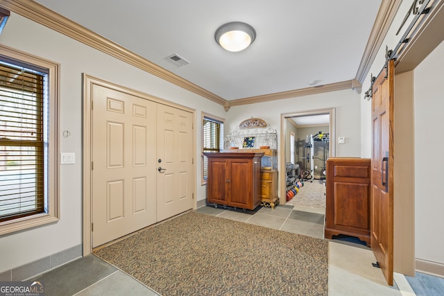 entrance foyer with light tile patterned floors, a barn door, visible vents, light colored carpet, and crown molding