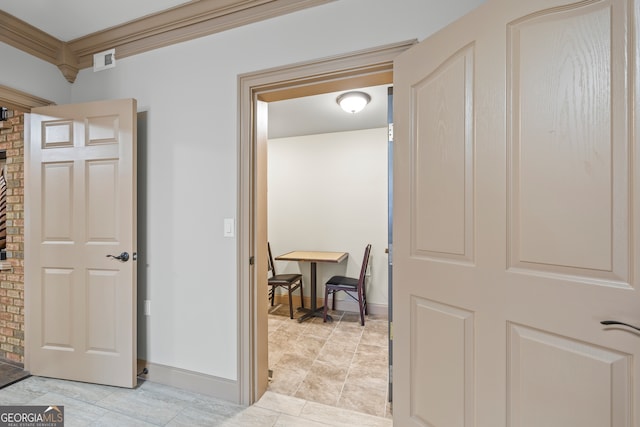 hallway featuring ornamental molding, visible vents, and baseboards