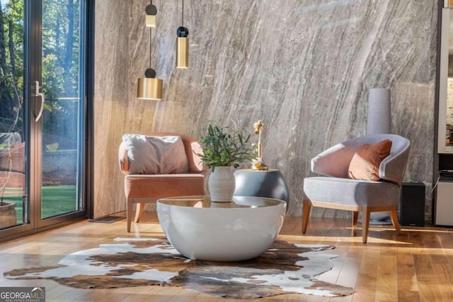 living area with a wealth of natural light, light hardwood / wood-style floors, and expansive windows