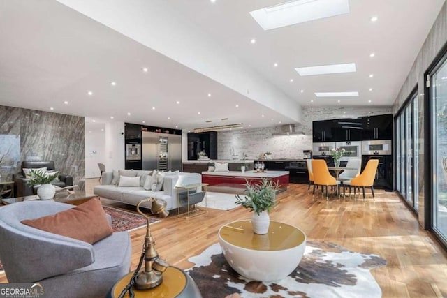 living room featuring a skylight, expansive windows, a healthy amount of sunlight, and light wood-type flooring