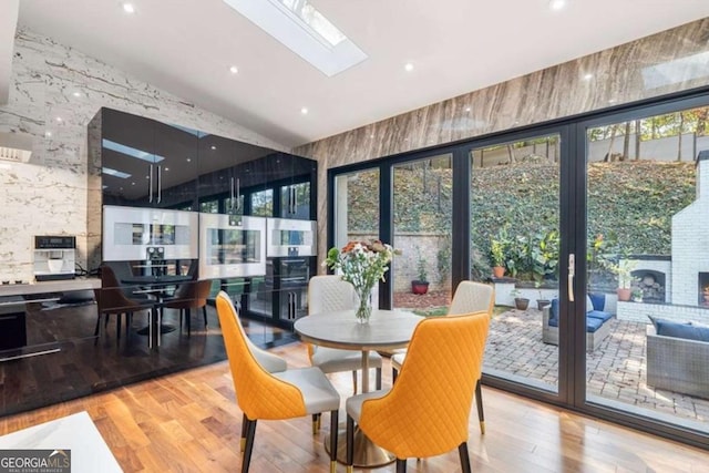 dining area with a skylight and light hardwood / wood-style flooring