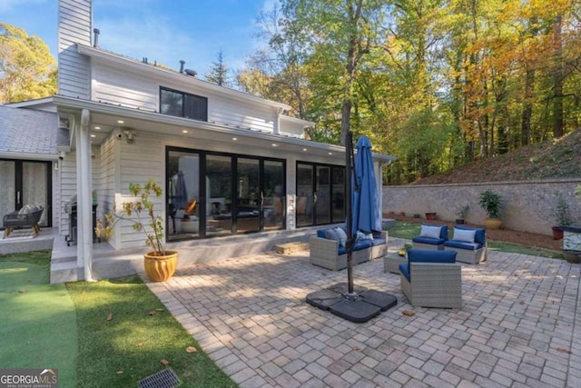 rear view of house featuring an outdoor living space and a patio area