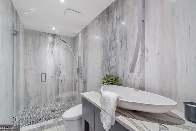 bathroom with vanity, tile walls, toilet, and walk in shower