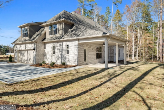 rear view of house featuring a garage, a patio, and a lawn