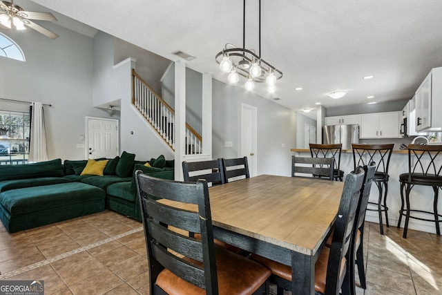 dining room with light tile patterned flooring, ceiling fan, and a towering ceiling