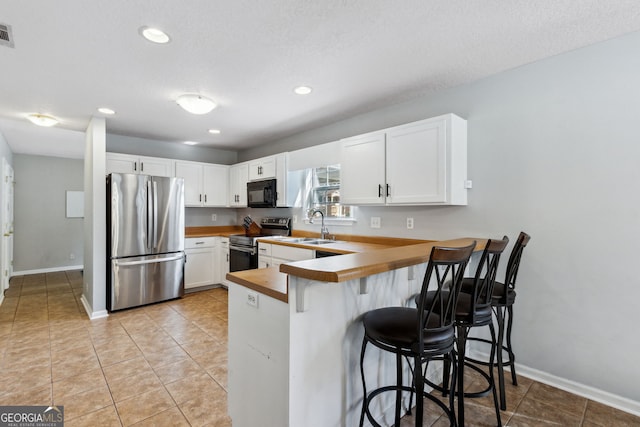 kitchen with a breakfast bar, sink, white cabinetry, kitchen peninsula, and stainless steel appliances