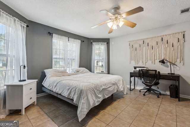 tiled bedroom with ceiling fan and a textured ceiling