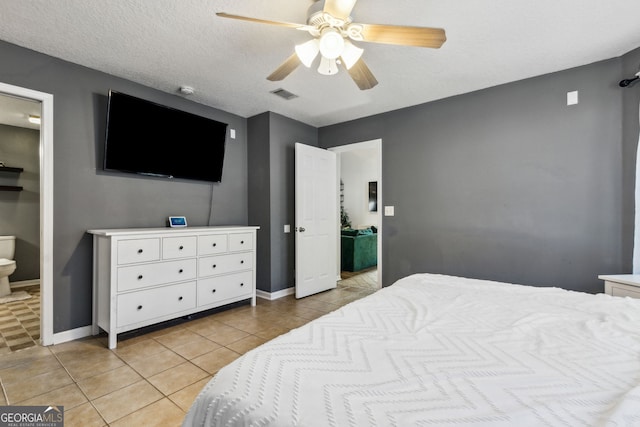 tiled bedroom featuring ceiling fan, ensuite bathroom, and a textured ceiling