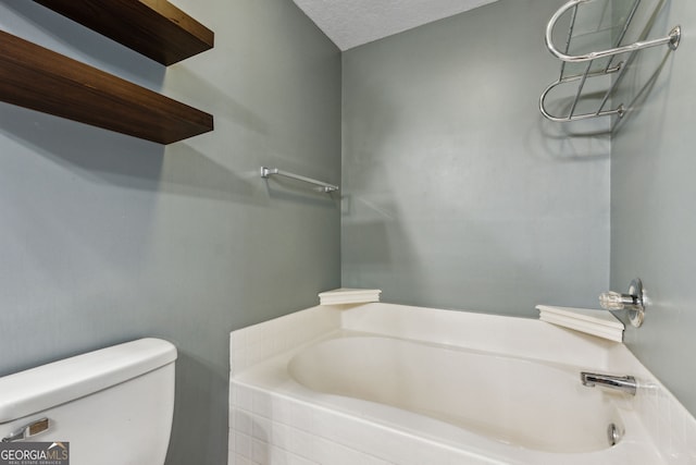 bathroom featuring a bathing tub, a textured ceiling, and toilet