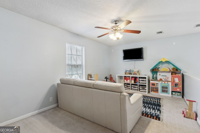 living room with ceiling fan, light colored carpet, and a textured ceiling