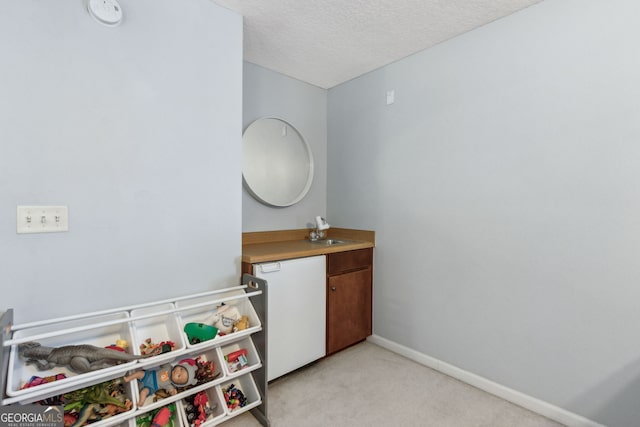 game room featuring sink, light carpet, and a textured ceiling