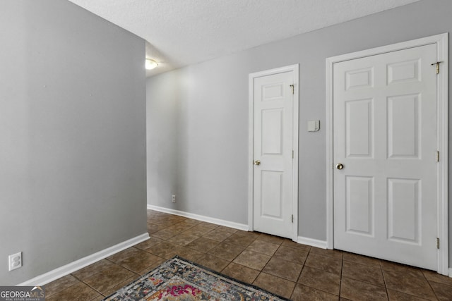 tiled empty room with a textured ceiling