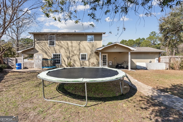 back of property featuring a trampoline and a yard