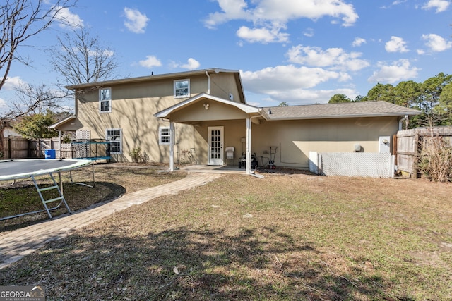 back of house featuring a yard, a trampoline, and a patio area