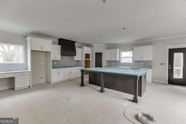 kitchen with decorative backsplash, white cabinets, and ornamental molding