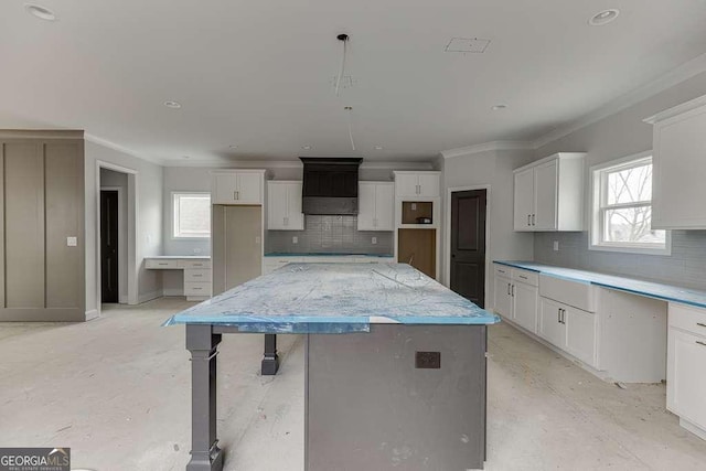 kitchen with backsplash, white cabinets, a kitchen island, and ornamental molding