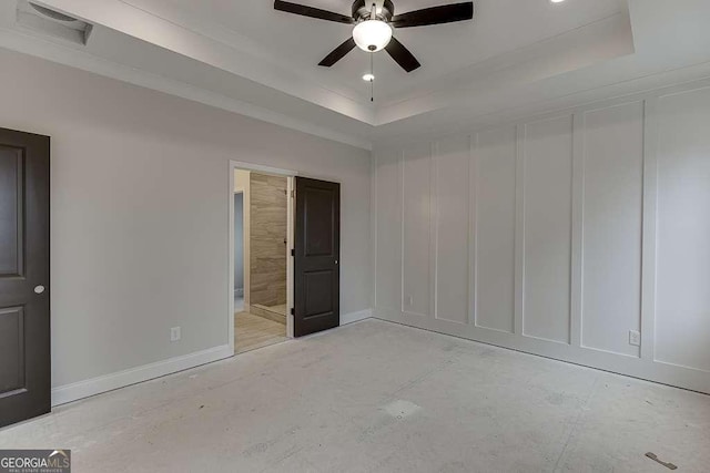 unfurnished bedroom with a tray ceiling, baseboards, visible vents, and a decorative wall