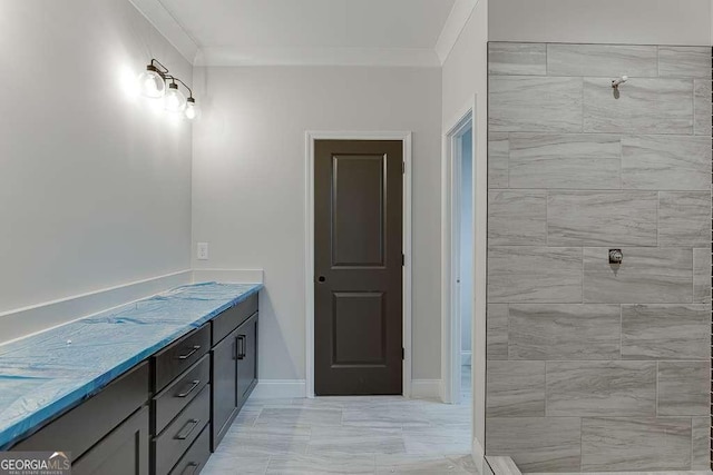 full bath with tiled shower, vanity, baseboards, and ornamental molding