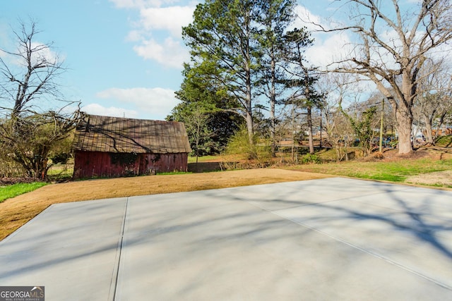 view of patio with basketball hoop and an outdoor structure