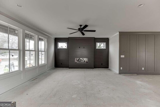 unfurnished living room featuring baseboards, crown molding, and a ceiling fan