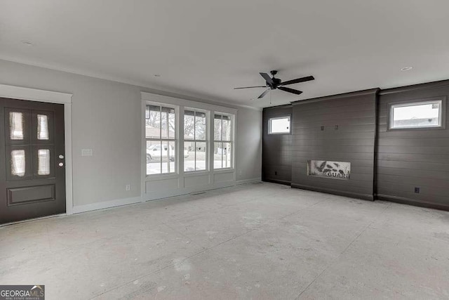 unfurnished living room featuring a wealth of natural light, baseboards, and a ceiling fan