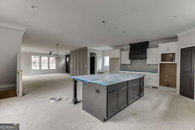 kitchen featuring a kitchen island, backsplash, white cabinetry, and crown molding