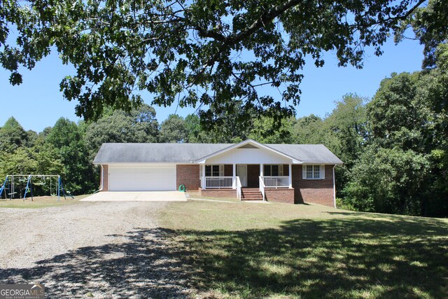 ranch-style home featuring a garage, a front yard, covered porch, and a playground