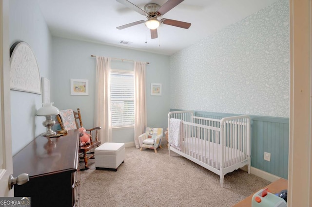 bedroom featuring ceiling fan, carpet, and a crib