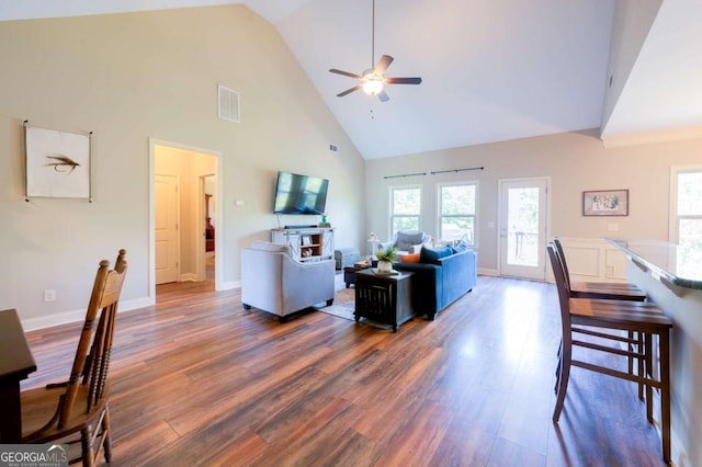 living room with dark wood-type flooring, ceiling fan, and high vaulted ceiling