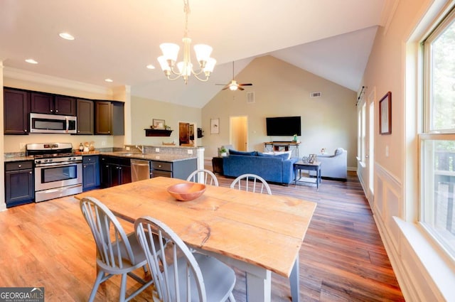 dining room featuring ceiling fan with notable chandelier, wood-type flooring, lofted ceiling, sink, and crown molding