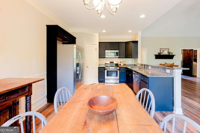 dining area with sink, light hardwood / wood-style floors, light stone countertops, kitchen peninsula, and a chandelier