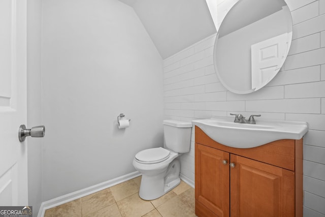 bathroom with vanity, vaulted ceiling, tile patterned floors, and toilet