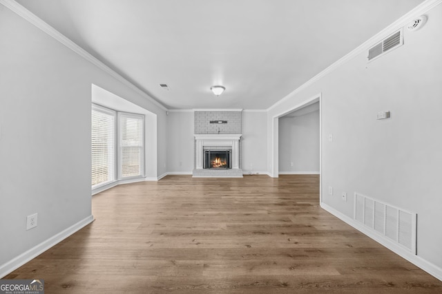 unfurnished living room featuring hardwood / wood-style floors, a fireplace, and ornamental molding