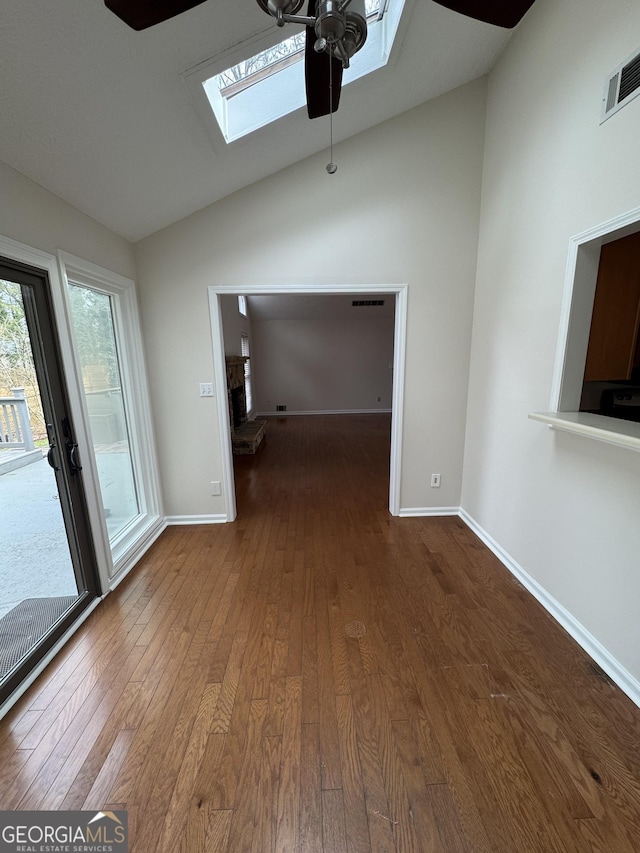 spare room featuring ceiling fan, vaulted ceiling with skylight, and hardwood / wood-style floors